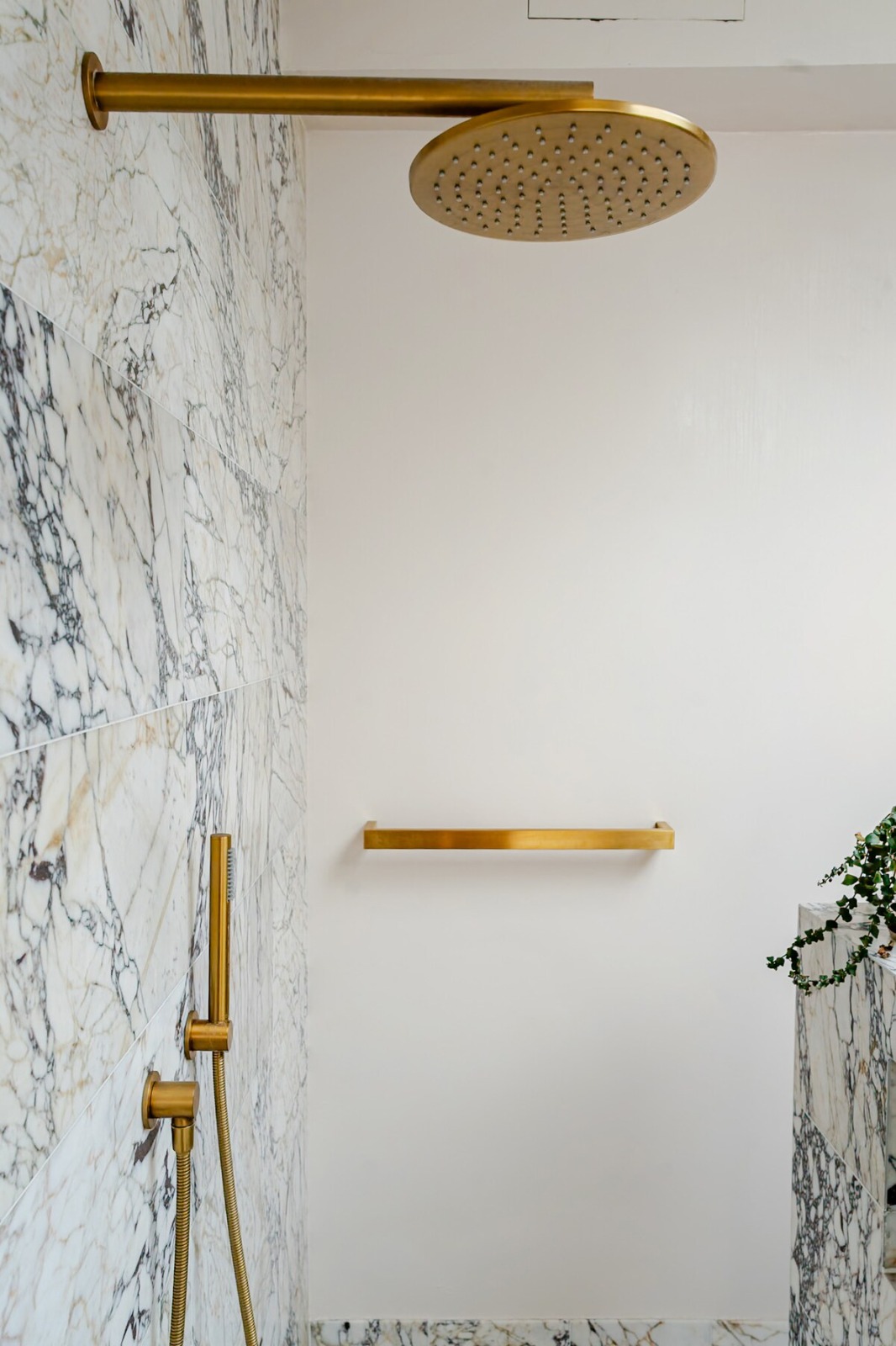 Brass rainfall shower against calacatta viola marble